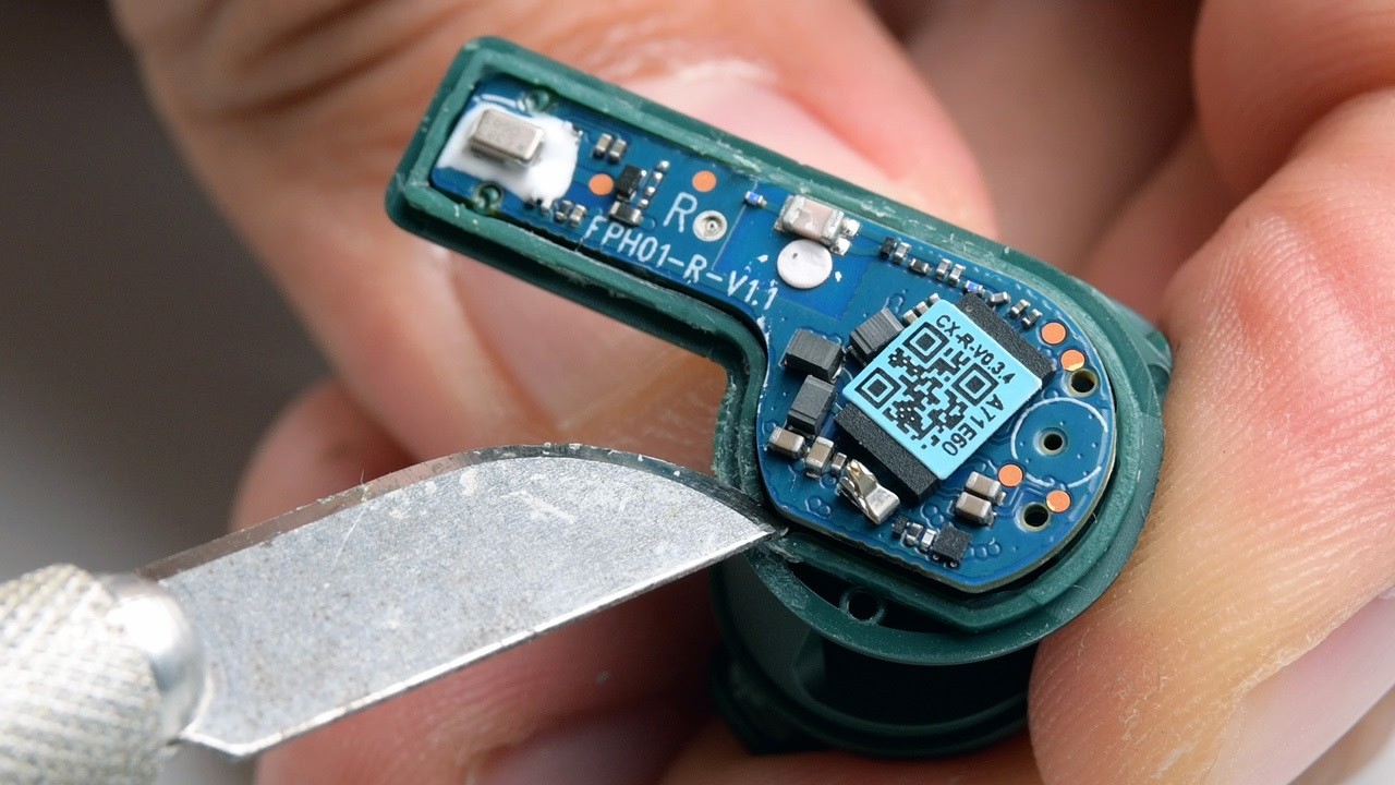 A Fairbuds 2 earbud circuit board being pried out with a hobby knife