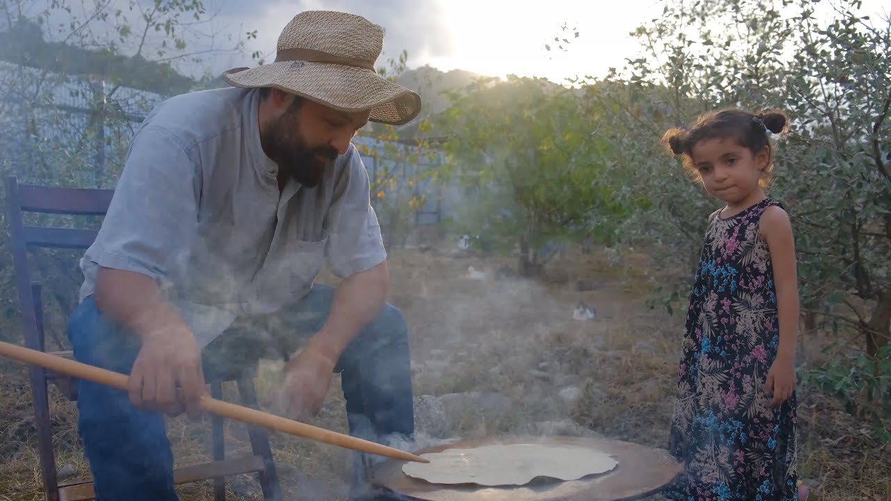 Семейная деревенская кухня: отец готовит кебаб из мяса и баклажана в тандыре