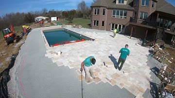 Laying travertine pavers for a large pool deck.