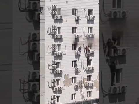 Beijing, China - People clinging onto windows of a building after fire ravages a hospital. 12 dead.