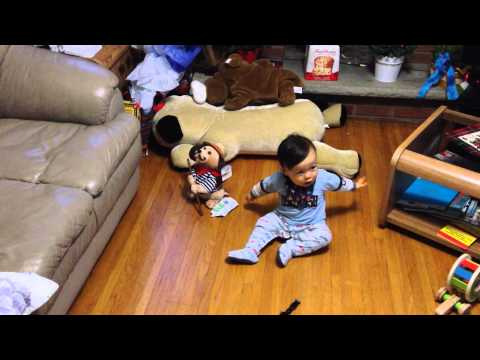 Kylin dancing on his butt in front of a stuffed dog