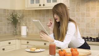 Beautiful girl eats sandwich and uses tablet