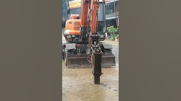 Máy xúc đục bê tông giữa trời mưa