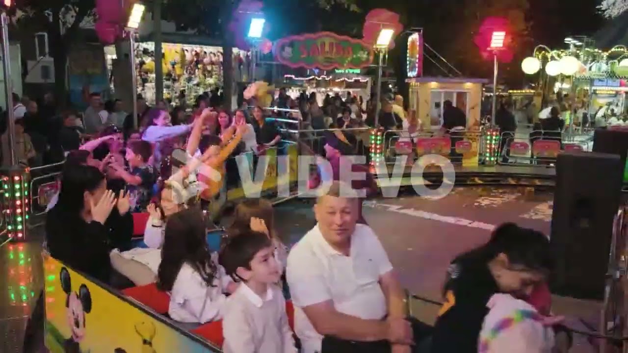 San Froilán Carnival at nighttime, people having fun riding Toy train Playground, Lugo City, Spain