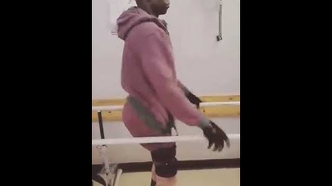 A paraplegic guy trying to walk again by holding parallel bars.