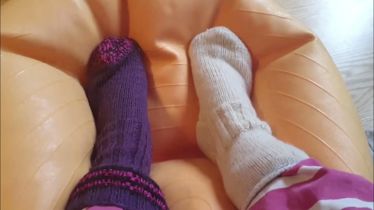 Feet squashing and deflating a exercise ball. In a jumpsuit and knitted
