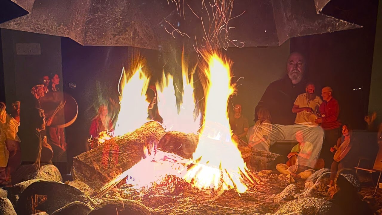 A sacred fire gathering at night, with people seated around the flames, from a spiritual family retreat