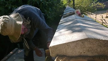 Laying large coping stones on a 12 foot Victorian wall.