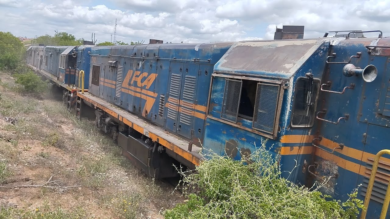 TREM CARGUEIRO PUXANDO DUAS LOCOMOTIVAS REBOCADAS E VAGÕES DE CROMO VAZIOS