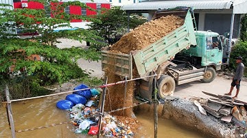 The nice project and skill bulldozer driver push stone cover trash fill up land dump truck unload