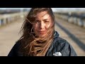 Hot Brunette Woman With Long Hair Wearing a Windbreaker Coat Waits in Very Strong Winds, Gale Force