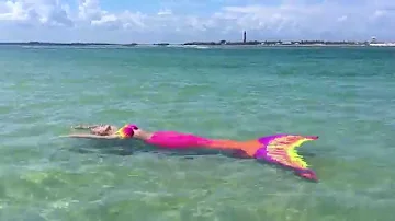 Colorful fluorescent neon mermaid at lighthouse beach