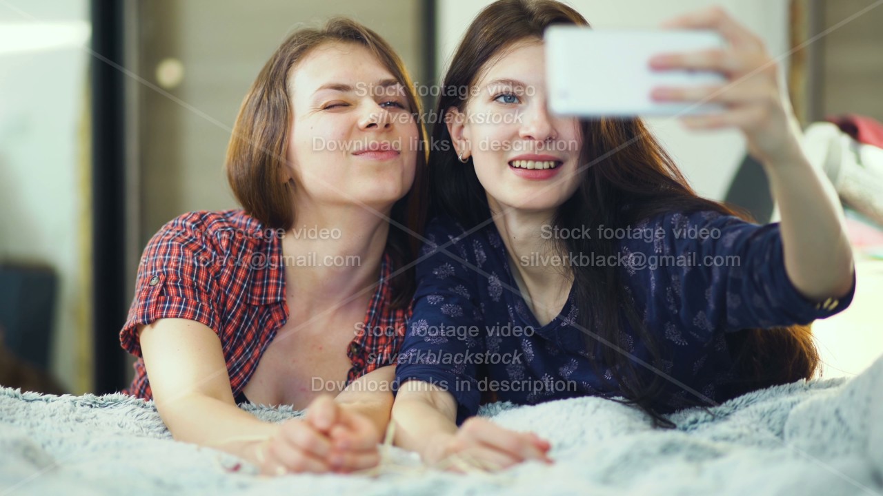 Two happy women friends lying in bed and making selfie in morning and ...