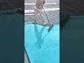 A worker is using a long-handled squeegee to spread light blue epoxy flooring