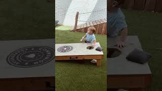 Bean bag hits little boy then bounces off his head and lands in corn hole game