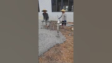 Two masters pouring concrete with a pipe and skillfully leveling the ground