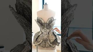 Orchid petals made from silver threadwork and beads are placed onto a corset bodice.