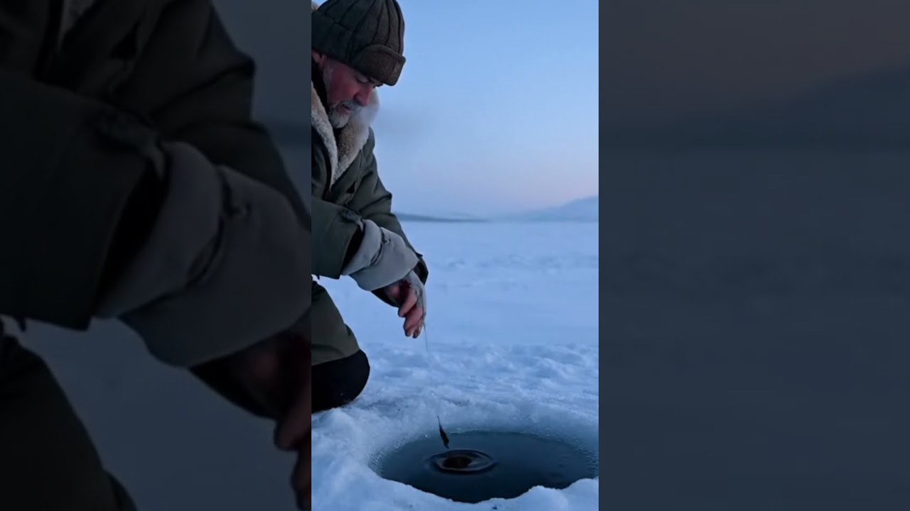 Man Fishing Through Ice Hole in Arctic Landscape 