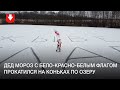 Дед Мороз с бело-красно-белым флагом катается на коньках по озеру недалеко от Полоцка