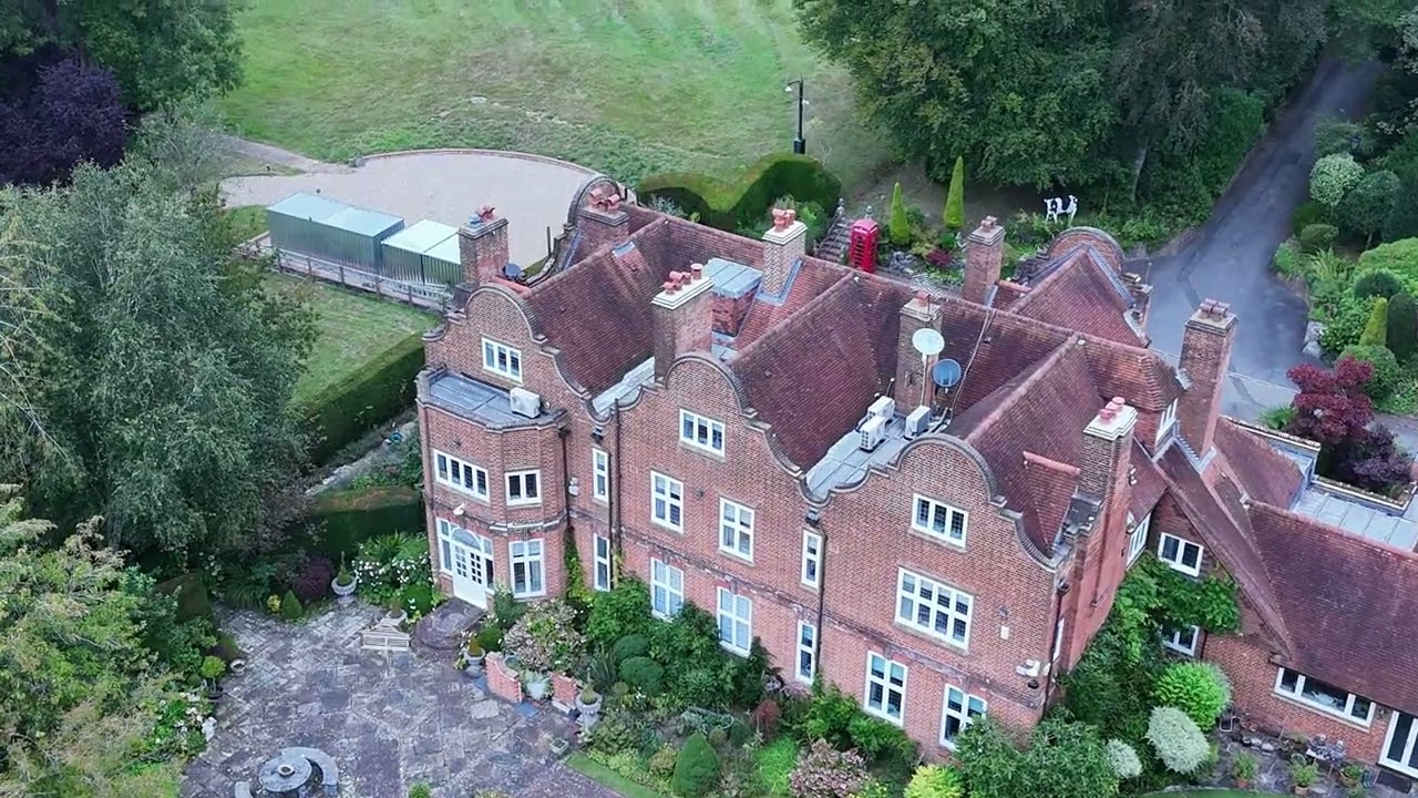 Aerial view of Ozzy Osbourne’s historic country mansion in the English countryside, featuring red brick walls, ornate gables, and landscaped gardens.