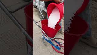 Farmer Pouring Seeds into a Manual Push Seeder