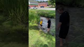 Boy and his brother jump into water than older boy slips on his way out and faceplants on grass