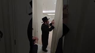 Skulen Rebbe of Lakewood hanging a Mezuzah