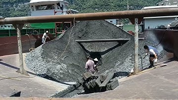 Barge unloading phosphate rock - The cargo was difficult to unload because the barge was too flat