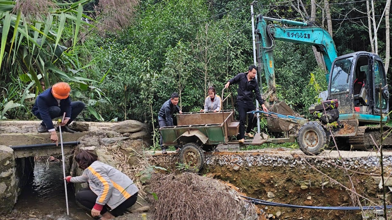 The excavator demolished the road to make a drain for the river.