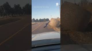 Missouri State Highway Patrol trooper shows off strength as he pushes a hay bale off a road