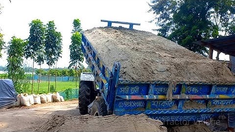 River sand is load and unloading by digital hydraulic system next to narrow road building Sonalika