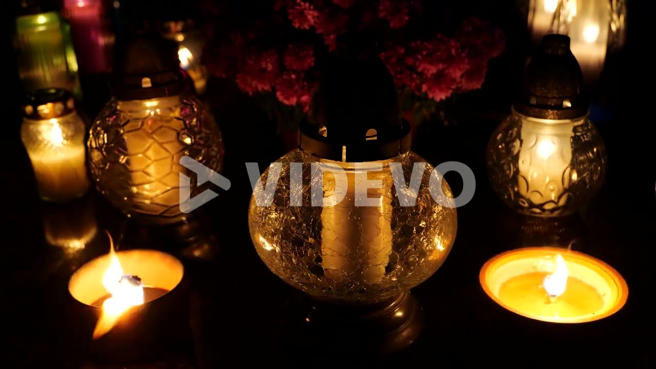 Grave candle lights burning at night on cemetery tomb