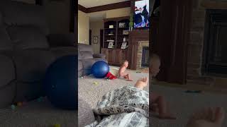 Boy with mullet hairdo jumps from couch onto exercise ball in diaper but misses and lands on rear