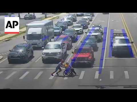 Man dressed as Spider-Man helps a person in a wheelchair cross the road
