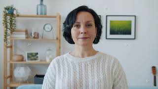 Good-looking mature woman turning to camera smiling standing alone indoors