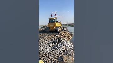 The heavy machine Shantui bulldozers pushing rock for backfill on the development Area.