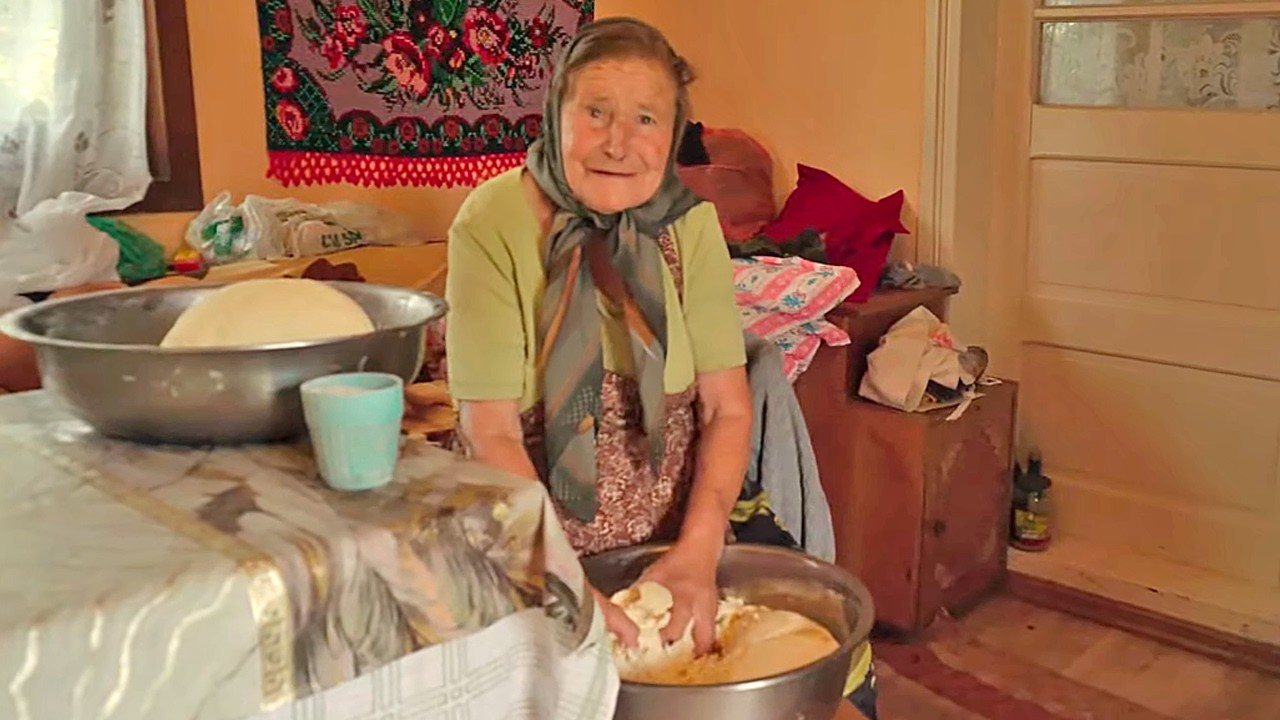 Happy old woman making cheese in a mountain village of Transylvania