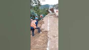 Workers are using hammers to trim the slopes beside the newly constructed road.
