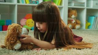 Cute liitle girl talking and hugging her teddy bear while lying on the floor. Girl taking care of screenshot 5