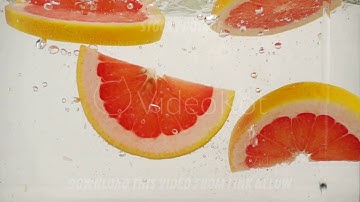 Round grapefruit slices slowly sink in water, slow motion close-up