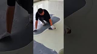 applying smooth white self leveling epoxy coating over a dark grey indoor floor surface using