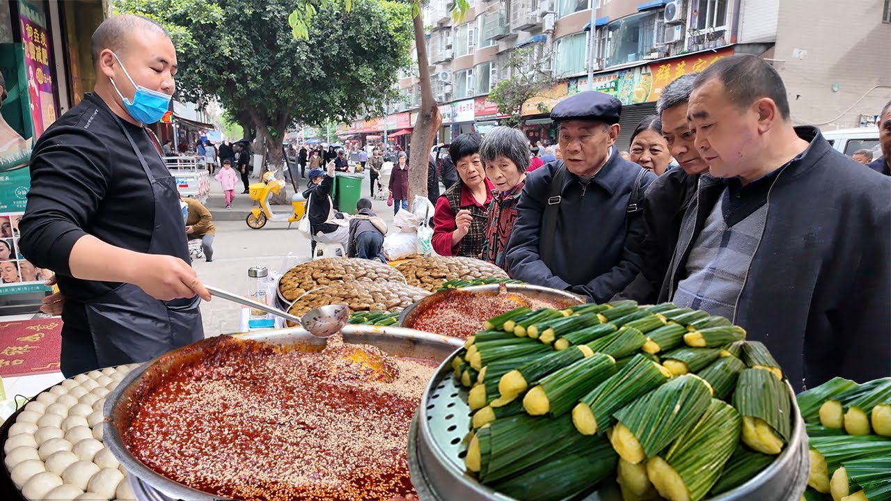 中国四川乐山早市美食，新鲜出炉的叶儿粑，挂满糖浆的甜皮鸭，牛肉肥肠在一起称为鸳鸯，著名的牛华豆腐脑，排队购买的拔丝糖葫芦，新鲜出炉的锅巴馒头，现场制作的辣椒酱，乐山的街头美食多种多样。