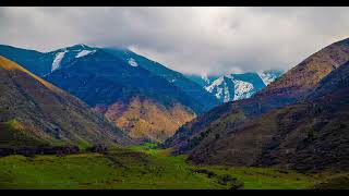 dense grey clouds floating over mountain range and casting shadows on green mountains slopes at