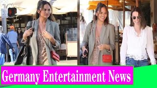 Chrissy Teigen cuts a chic figure in floral dress with olive hued blazer and boots for lunch in LA