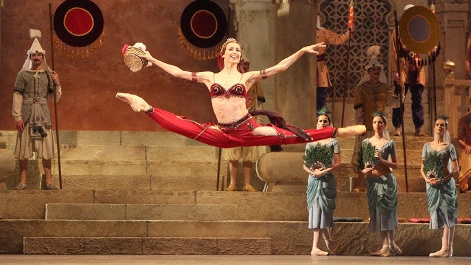 Una bambina ballerina sta ballando sul palco in tutù su scarpe da punta con  un tamburello, una variazione classica di esmeralda.