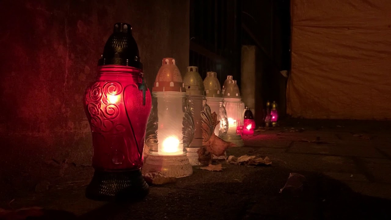 Setki zniczy i kwiatów pod zamkniętymi bramami cmentarza w Koszalinie