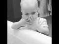 baby washes face in the bath tub