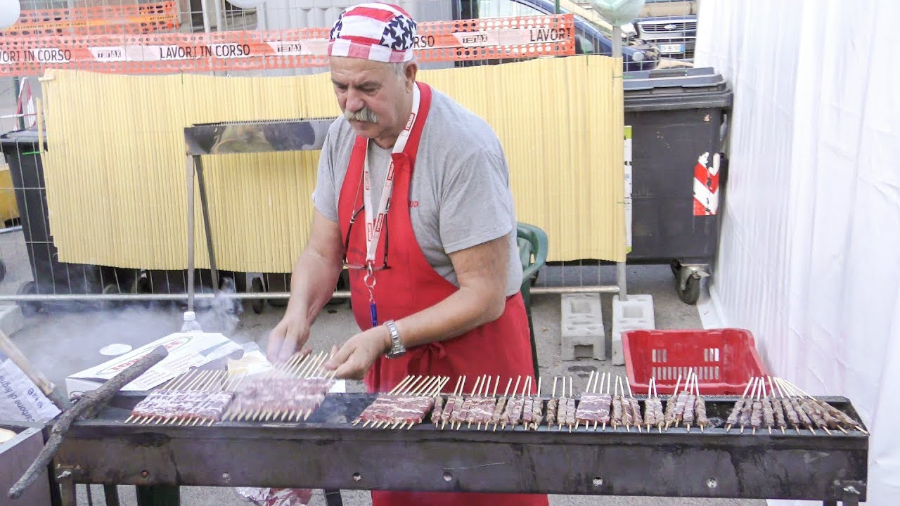 Pictoresque Man Cooking Small Lamb Skewers and Hanged Cheese on Fire