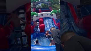 Girl goes down inflatable bounce house slide and crashes into little boy