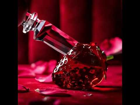 A crystal knife cuts a glass strawberry, its ruby fragments catching crimson spotlights